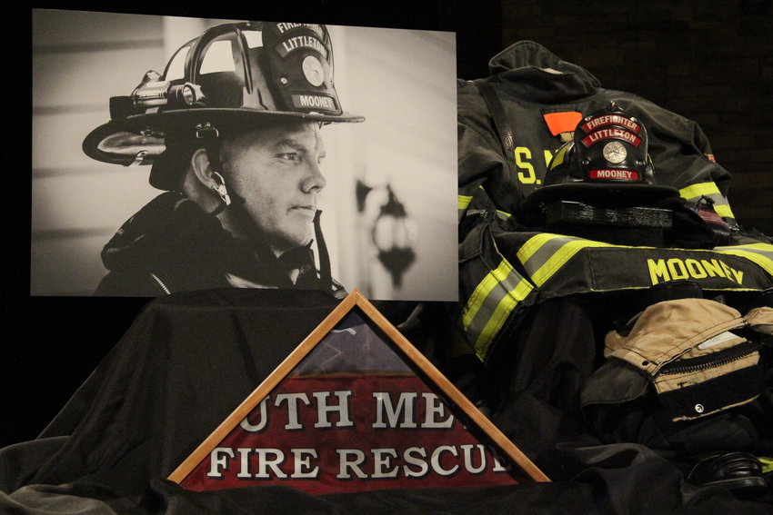 A photo of Cody Mooney and his firefighting helmet and gear sit on the stage at Mission Hills Church in Littleton March 8, where a memorial service was held for Mooney.